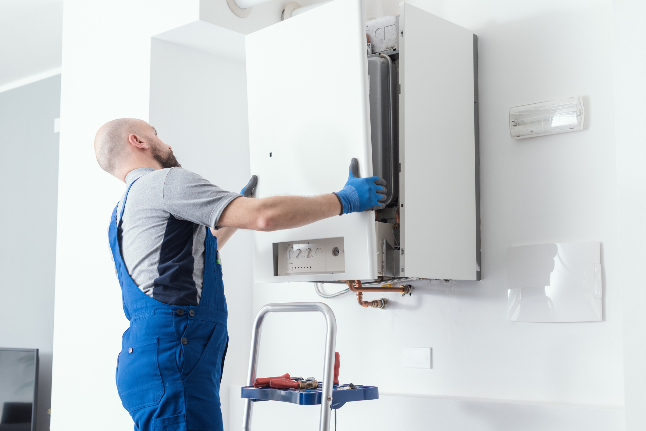 HVAC technician replacing the front panel of a boiler after replacing the unit