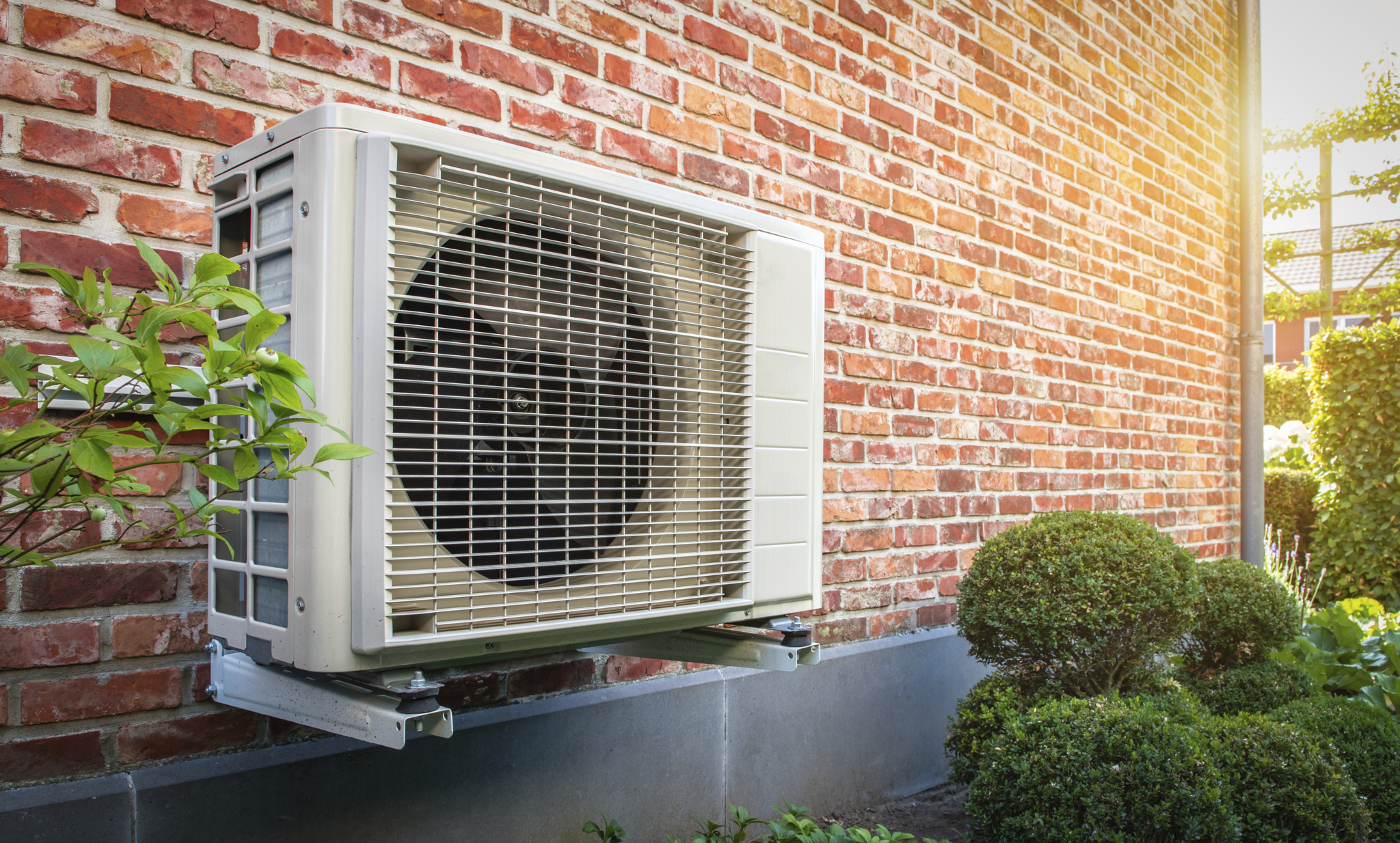 Heat pump mounted on wall outside brick home