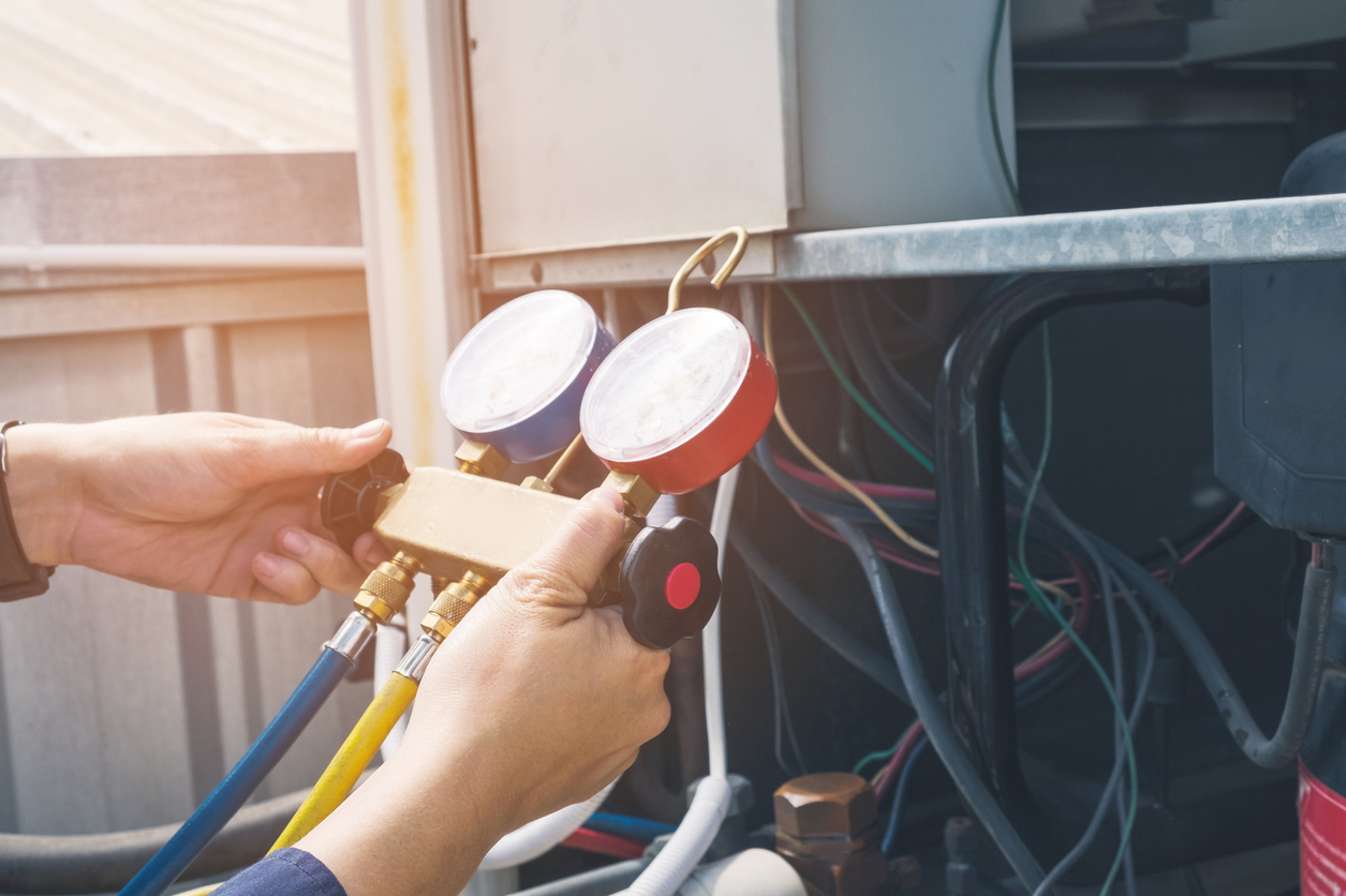 Hands on a pressure gauge checking a commercial HVAC unit